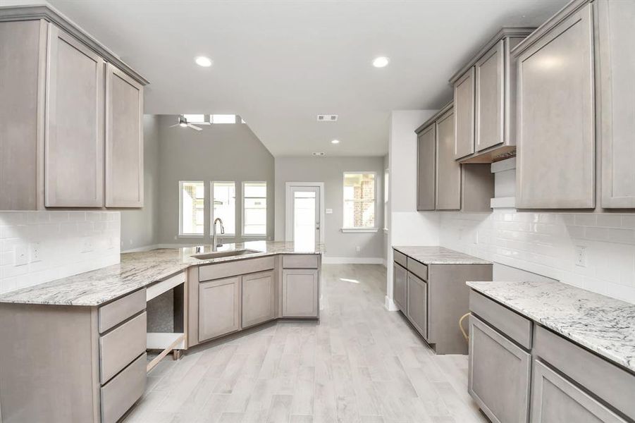 This kitchen is by far any chef’s dream! This spacious kitchen features high ceilings, light stained wood cabinets, granite countertop, SS appliances (To be Installed), modern tile backsplash, recessed lighting, extended counter space, granite kitchen island with deep single basin sink, and a walk-in pantry all overlooking your huge family room.