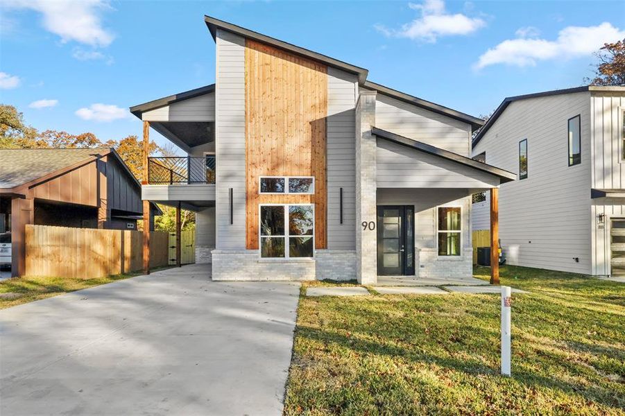 Modern home featuring a balcony and a front yard