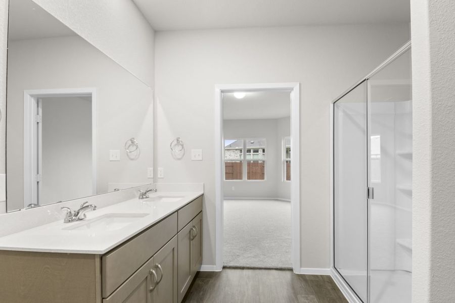 Image of a primary bathroom with a double white vanity with a large window and a white vinyl walk-in shower