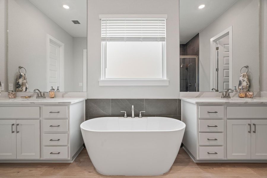Full bath with tile walls, light wood-style flooring, a stall shower, recessed lighting, and two vanities Full bath with tile walls, light wood-style flooring, a stall shower, recessed lighting, and two vanities