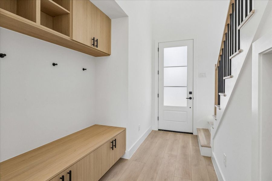Custom built in mudroom with Vicenza Oak cabinetry, upper storage, integrated bench seating, and matte black hooks keeps everyday essentials beautifully organized.