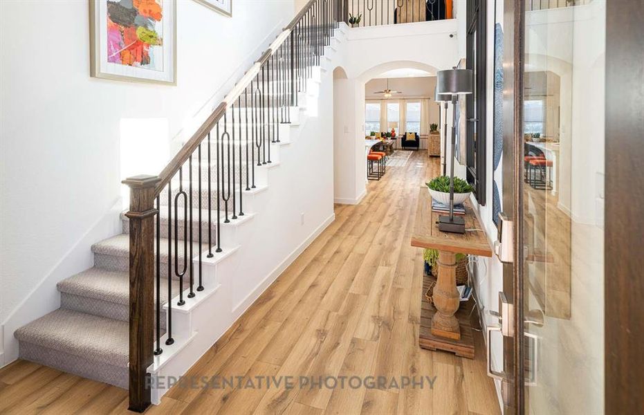Entryway featuring stairway, light wood-style flooring, arched walkways, and a high ceiling