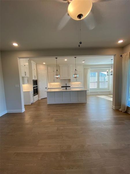 Kitchen with recessed lighting, hanging light fixtures, white cabinetry, open floor plan, and a ceiling fan Kitchen with recessed lighting, hanging light fixtures, white cabinetry, open floor plan, and a ceiling fan