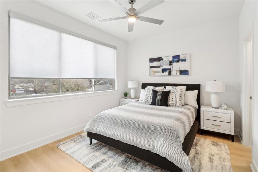 Bedroom featuring a ceiling fan, wood finished floors, visible vents, and baseboards