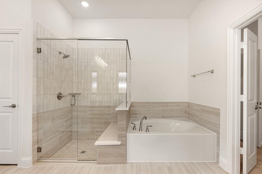 Master bathroom with glass-enclosed walk-in shower, built-in bench, and soaking tub with tile surround
