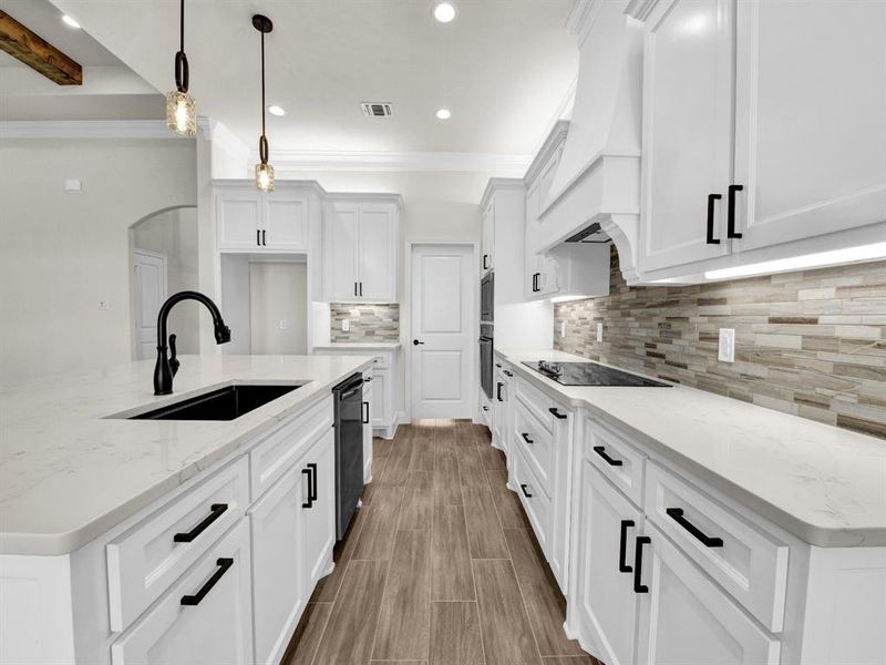 Kitchen featuring visible vents, white cabinetry, a sink, black electric stovetop, and custom range hood Kitchen featuring visible vents, white cabinetry, a sink, black electric stovetop, and custom range hood
