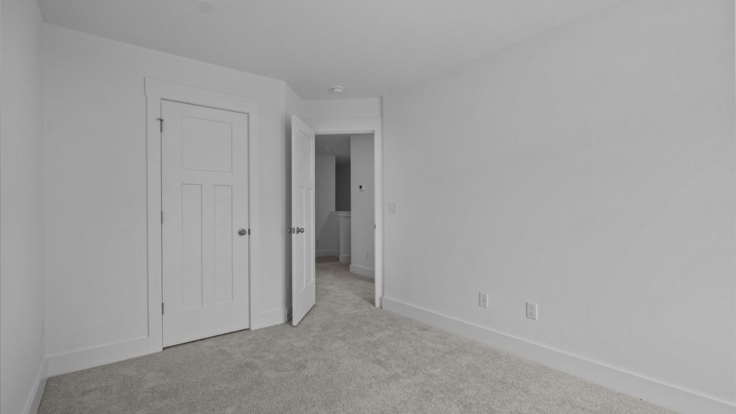 Tasteful secondary bedroom with plush carpet and a spacious walk-in closet Tasteful secondary bedroom with plush carpet and a spacious walk-in closet