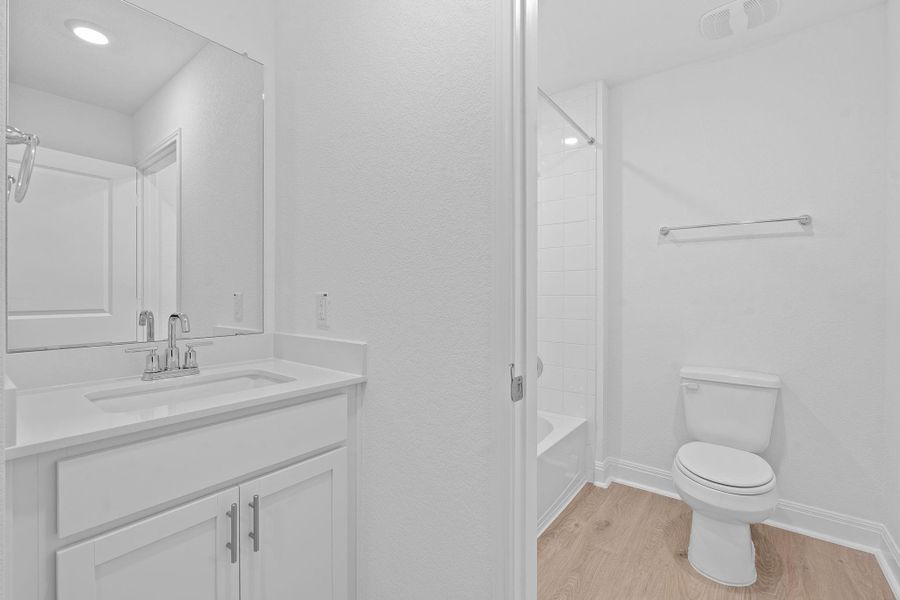 Full bathroom featuring light wood finished floors, vanity, and shower combination Full bathroom featuring light wood finished floors, vanity, and shower combination