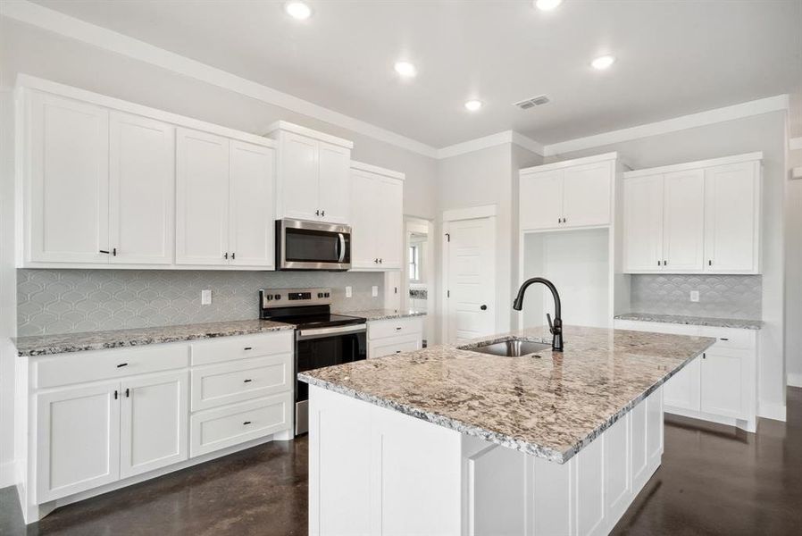 Kitchen featuring decorative backsplash, sink, stainless steel appliances, and white cabinetry