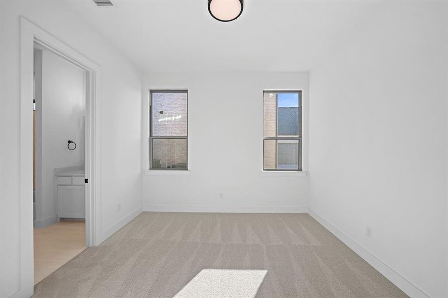 Unfurnished bedroom with light colored carpet and baseboards