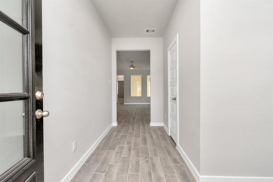 Greeted by a elegant glass front door, the entrance beckons with high ceilings, adorned with elegant wood-look tile flooring and oversized baseboards.