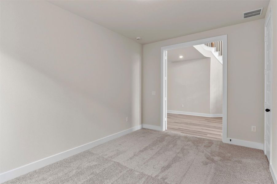 Unfurnished room featuring light colored carpet and stairs