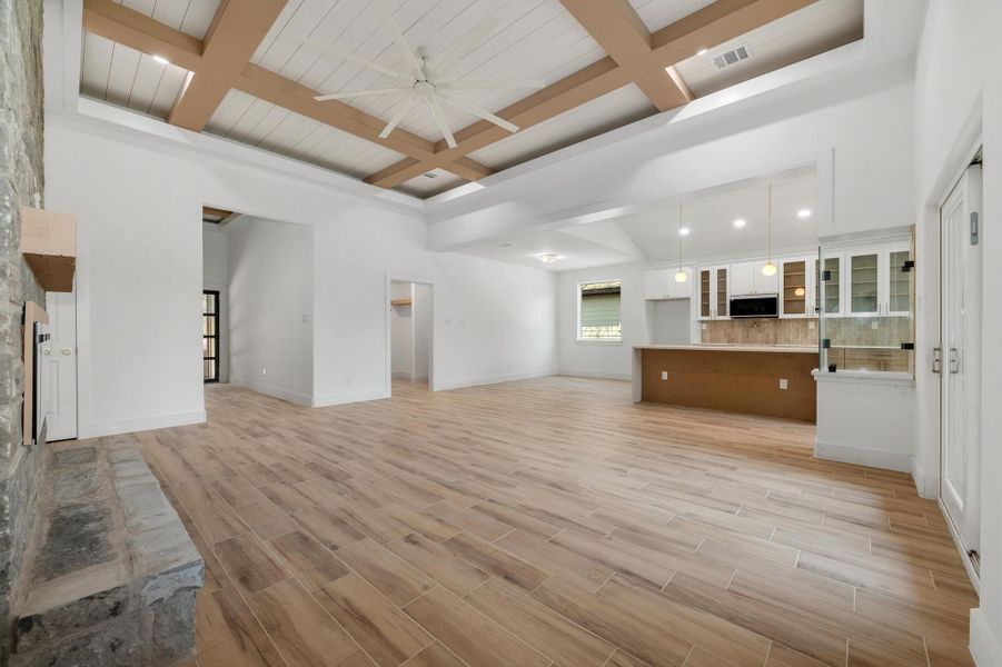 Living room with coffered ceiling, beam ceiling, wood finish floors, ceiling fan, and recessed lighting Living room with coffered ceiling, beam ceiling, wood finish floors, ceiling fan, and recessed lighting
