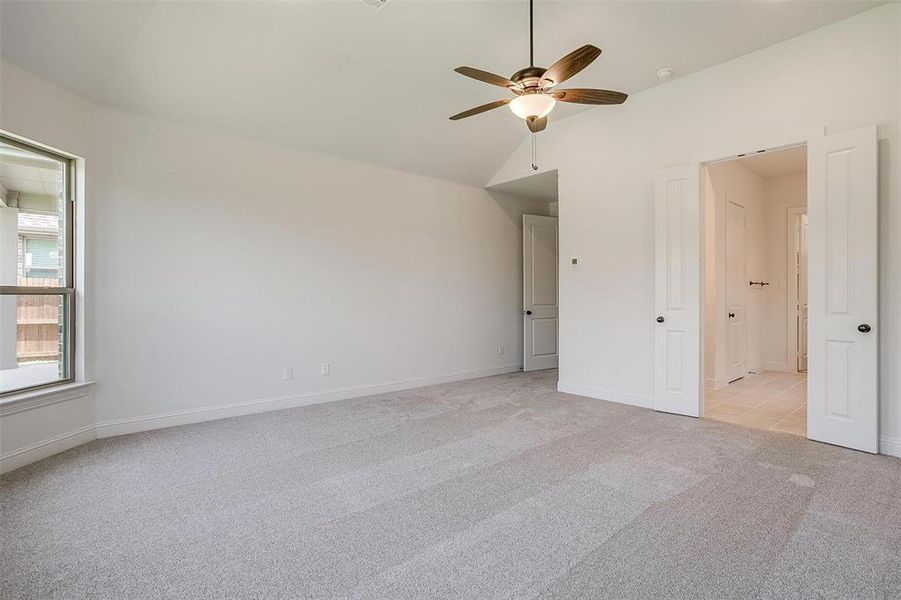 Spare room featuring light carpet, lofted ceiling, and ceiling fan