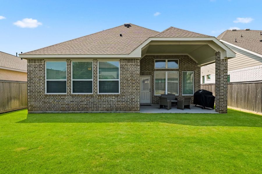 The rear of the home showcases attractive architectural detail and a seamless connection to the covered patio, creating an inviting extension of the living space that’s ideal for relaxing, dining outdoors, or entertaining guests.