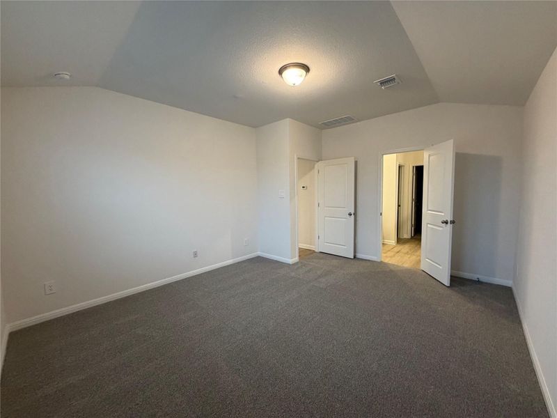 Unfurnished bedroom featuring vaulted ceiling and dark colored carpet Unfurnished bedroom featuring vaulted ceiling and dark colored carpet