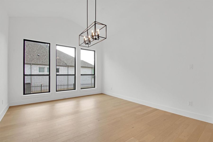 Formal Dining area with light hardwood floors, lofted ceiling, and a light chandelier