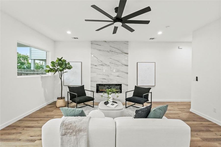 Living room with light hardwood / wood-style flooring, a premium fireplace, and ceiling fan