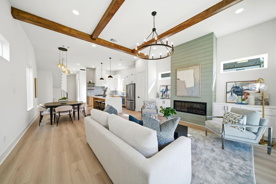 This photo showcases a bright, open-concept living and dining area with modern finishes. It features light wood flooring, a cozy fireplace, and stylish chandeliers.