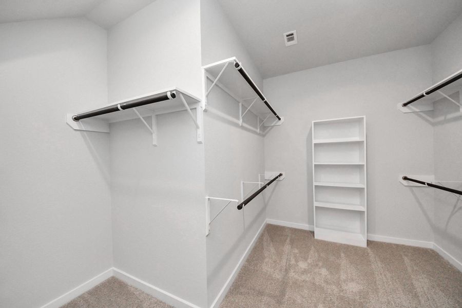 Walk-in closet that epitomizes luxury and practicality. This generously sized space features built-in shelving, offering abundant room for impeccable organization. High ceilings and recessed lighting create a bright and welcoming ambiance. Sample photo of completed home with similar floor plan. Actual colors and selections may vary.