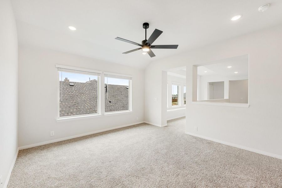 Empty bedroom with carpet, black ceiling fan, vaulted ceiling, and large windows
