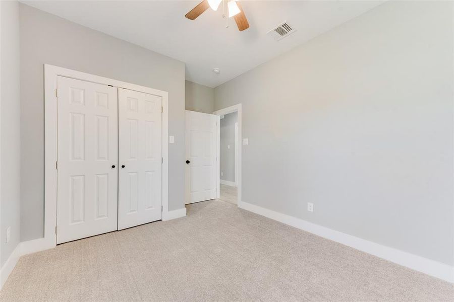 Unfurnished bedroom featuring light colored carpet, a closet, and ceiling fan