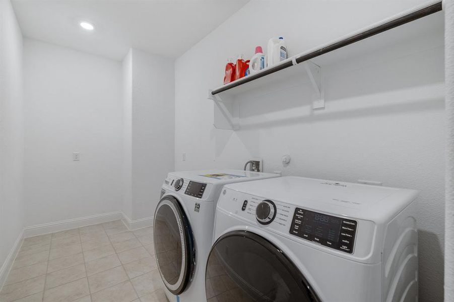 Laundry area featuring laundry area, baseboards, washer and clothes dryer, and light tile patterned flooring