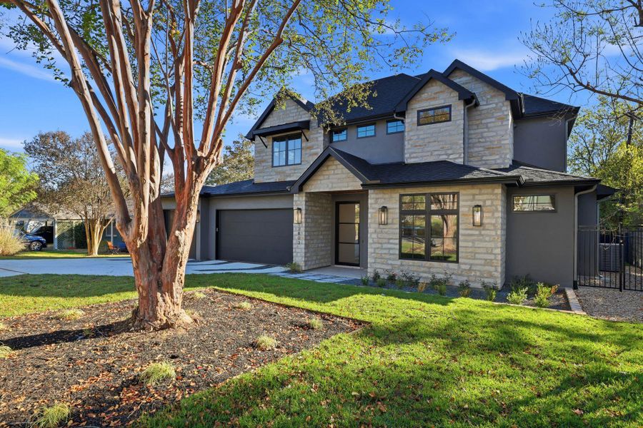 View of front of property featuring stone siding, a garage, and concrete driveway