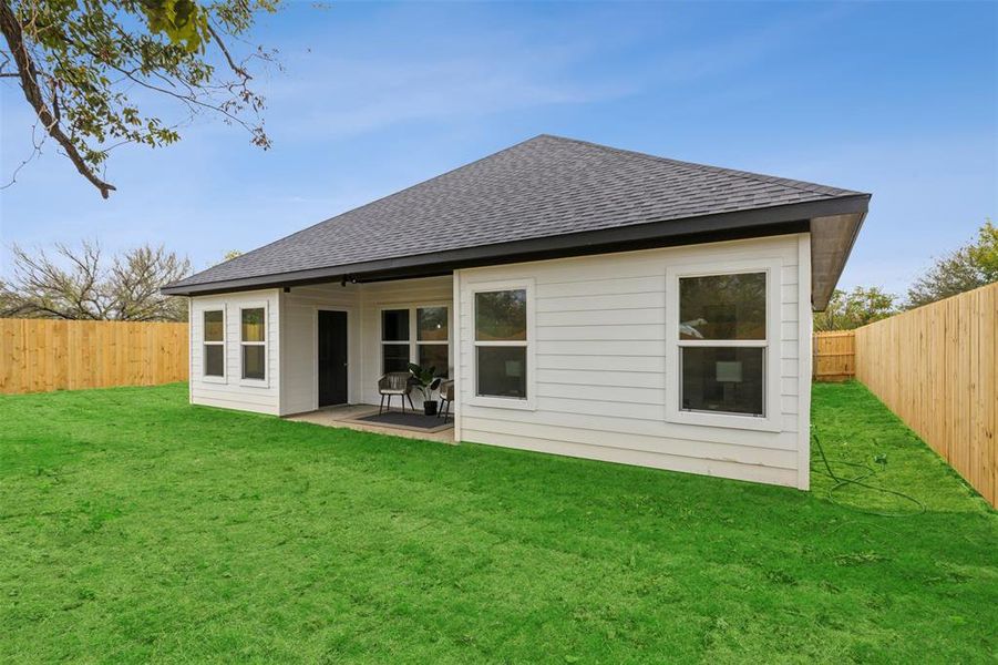 Rear view of property featuring a lawn and a patio area