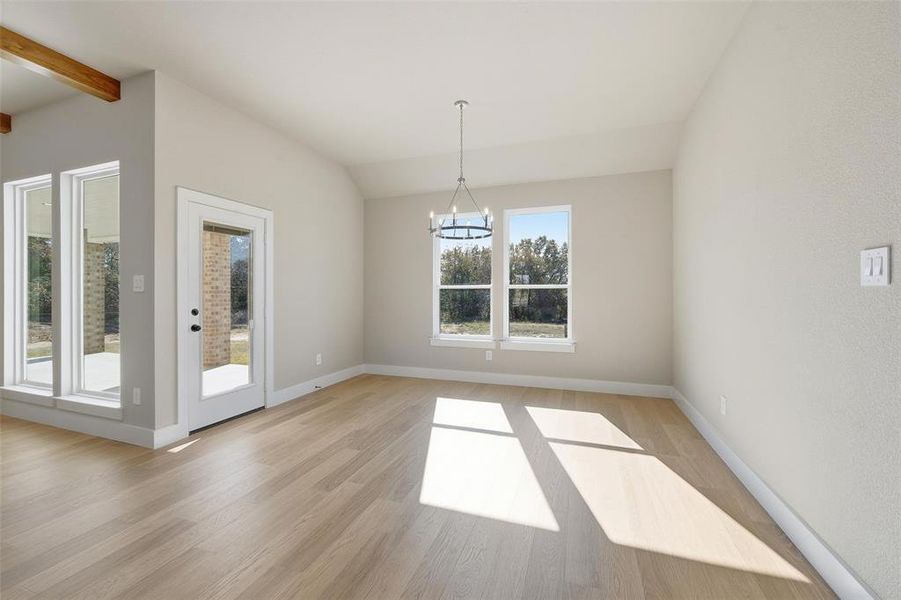 Unfurnished dining area with a chandelier, light wood-style flooring, and vaulted ceiling Unfurnished dining area with a chandelier, light wood-style flooring, and vaulted ceiling