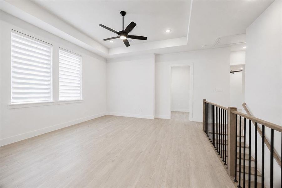 Spacious upper-level room featuring wood-finish flooring, two large windows with blinds, a modern ceiling fan, and recessed lighting
