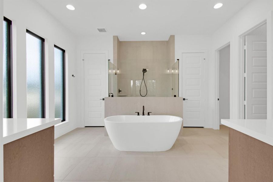 Primary Bathroom featuring double vanities, walk in shower, a freestanding tub, a large shower stall with bench seat, recessed lighting, and light tile patterned floors