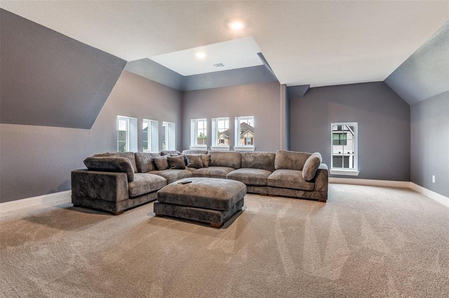 Carpeted living area with vaulted ceiling and baseboards