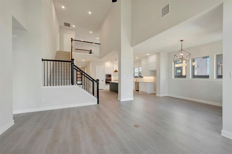 Unfurnished living room with a chandelier, a high ceiling, and light wood-style floors