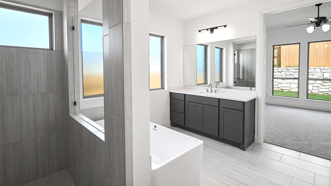 Full bath featuring a walk in shower, vanity, a soaking tub, and ceiling fan Full bath featuring a walk in shower, vanity, a soaking tub, and ceiling fan