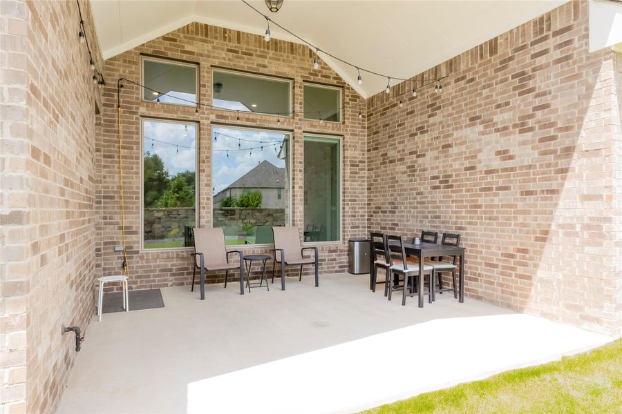 An inviting covered patio with brick walls and string lights sets the scene for relaxed outdoor living. Gas pipe for bbq.