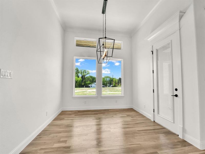 Unfurnished dining area featuring a chandelier, light wood-style floors, and baseboards Unfurnished dining area featuring a chandelier, light wood-style floors, and baseboards