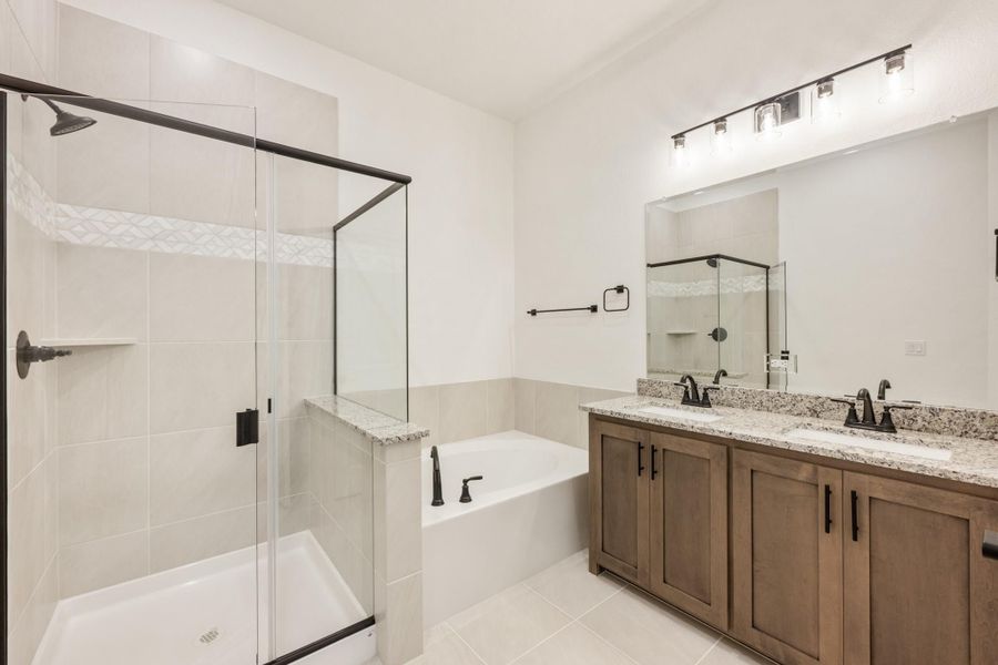 Bathroom with glass walk-in shower, soaking tub, and double vanity with granite countertops