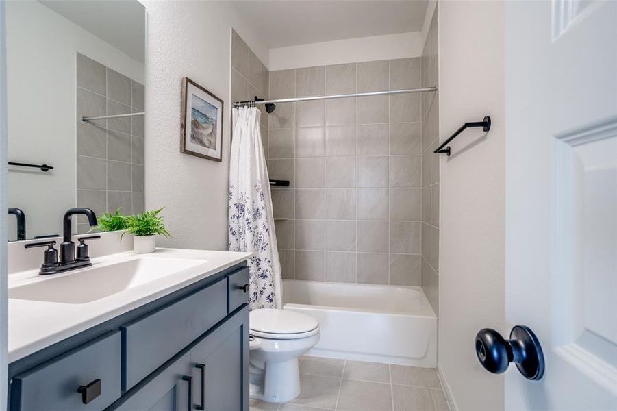Full bathroom featuring vanity, shower / bath combination with curtain, and light tile patterned floors