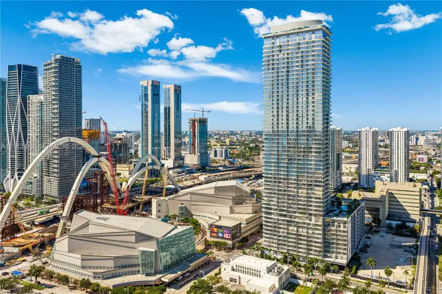 High-rise tower featuring a glass facade, private balconies, and a multi-level podium base situated within an urban center