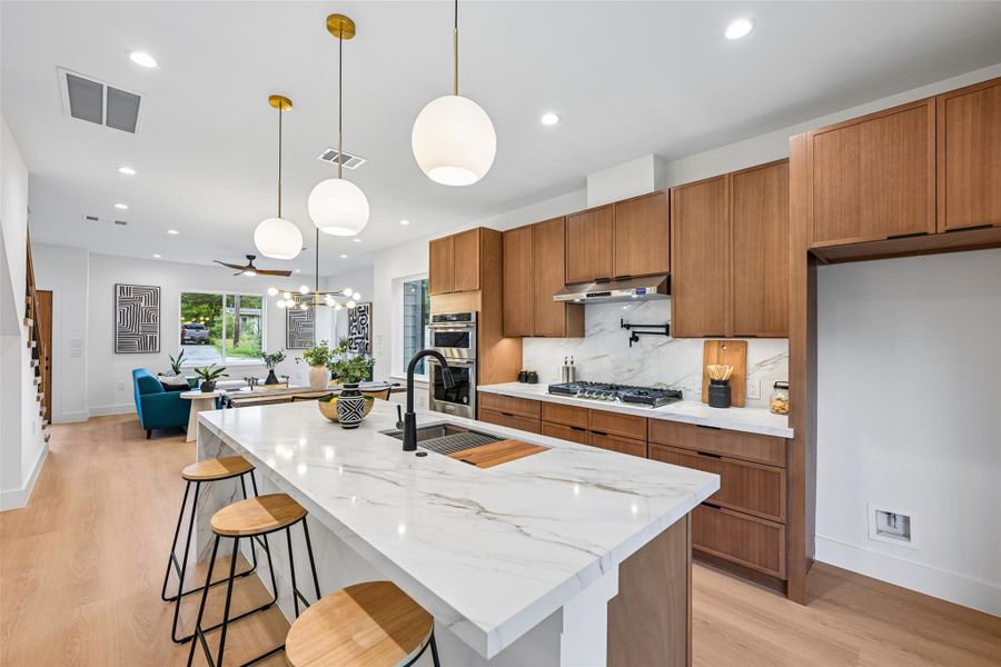 Culinary excellence awaits in this open-concept kitchen, featuring a spacious island with seating and sophisticated pendant lighting.