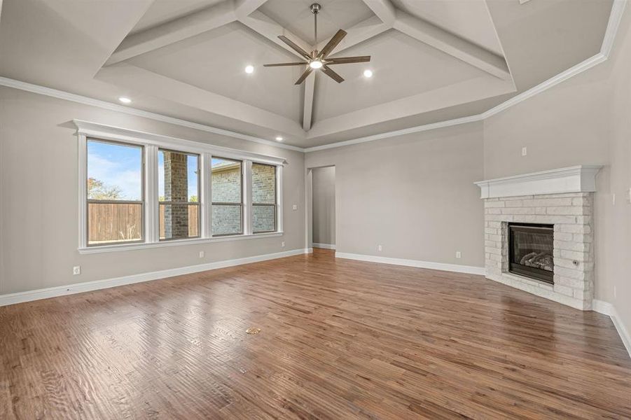 Unfurnished living room with a brick fireplace, light wood-type flooring, ceiling fan, recessed lighting, and ornamental molding Unfurnished living room with a brick fireplace, light wood-type flooring, ceiling fan, recessed lighting, and ornamental molding