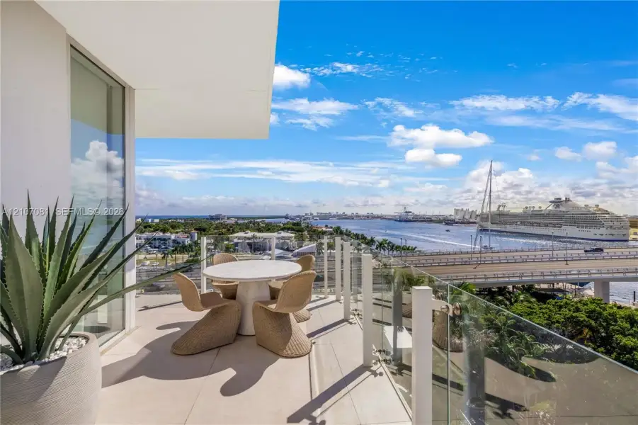 Covered balcony featuring oversized porcelain tile flooring and a transparent glass railing overlooking a waterway Covered balcony featuring oversized porcelain tile flooring and a transparent glass railing overlooking a waterway