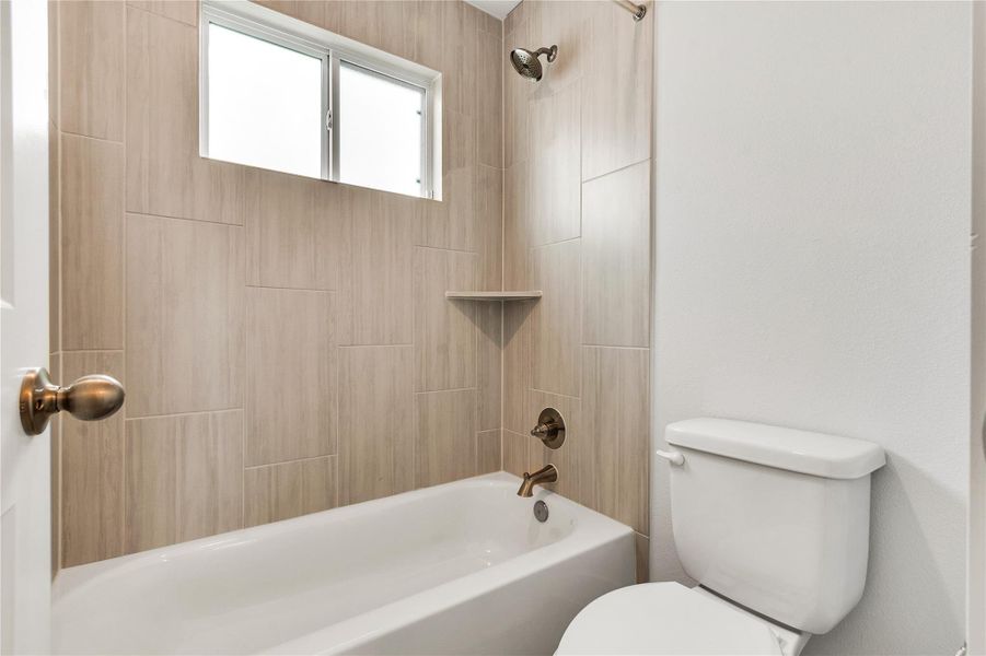 A window above the tub allows for natural light in this contemporary bath.