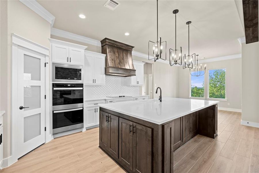 Kitchen with dark brown cabinetry, white cabinetry, decorative backsplash, wood tiled floors, and crown molding