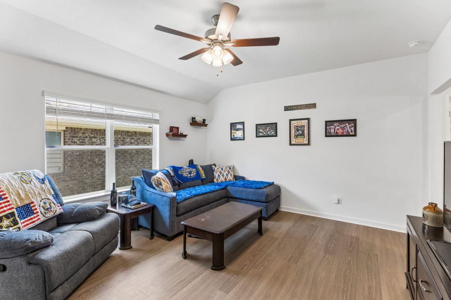 Spacious common area featuring vaulted ceilings, wood-finish flooring, and multiple windows