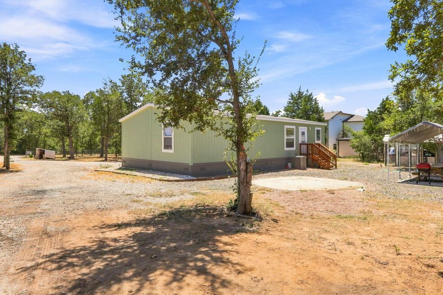 Mature trees surround this home featuring a wooden entry deck and a generous yard.