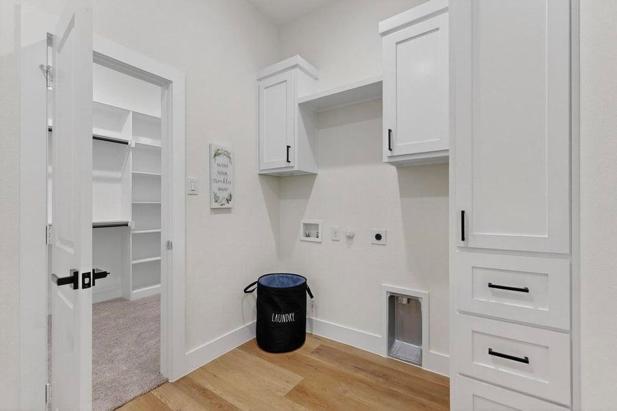Washroom featuring hookup for a gas dryer, light wood-type flooring, hookup for a washing machine, cabinet space, and electric dryer hookup Washroom featuring hookup for a gas dryer, light wood-type flooring, hookup for a washing machine, cabinet space, and electric dryer hookup