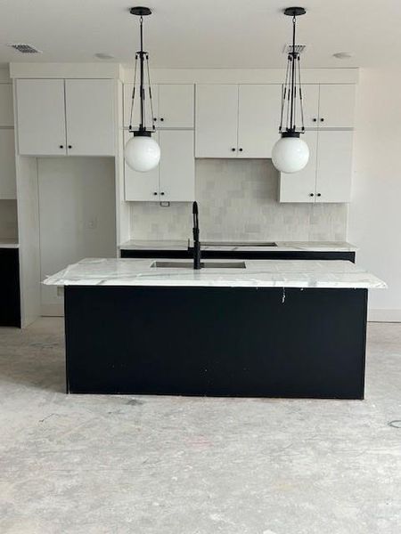 Kitchen includes stacked cabinets single bowl sink and pendent lighting.  Grea black and white combination.