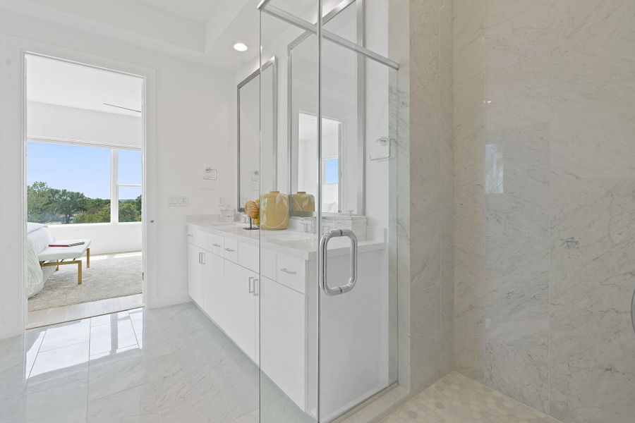 Full bath featuring double vanity, a marble finish shower, light marble finish flooring, and recessed lighting